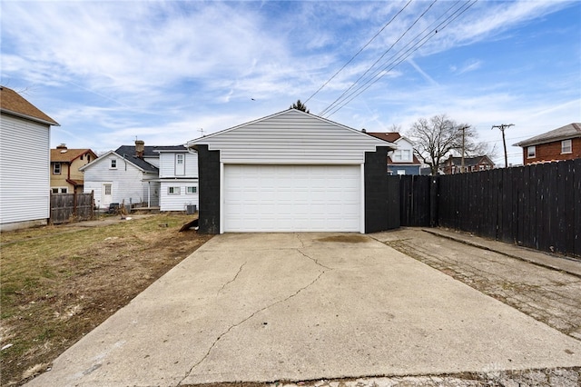 garage with concrete driveway and fence