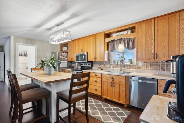 kitchen with a kitchen island, sink, wooden counters, decorative backsplash, and stainless steel appliances