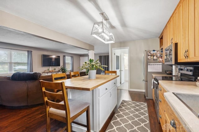 kitchen with dark hardwood / wood-style floors, wood counters, a kitchen bar, hanging light fixtures, and stainless steel appliances