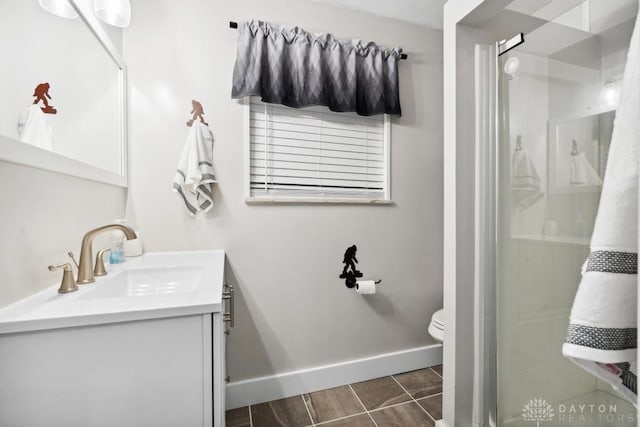 bathroom featuring vanity, a shower with shower door, and toilet