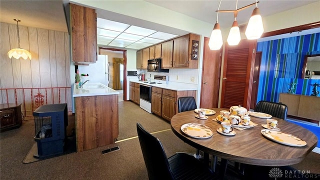 kitchen featuring white appliances, sink, carpet, and hanging light fixtures