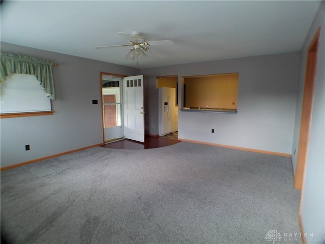 unfurnished living room with ceiling fan and dark colored carpet