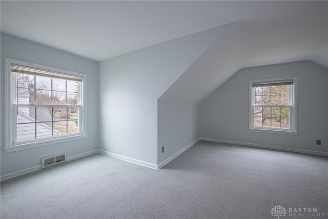 bonus room with lofted ceiling, a healthy amount of sunlight, and light colored carpet