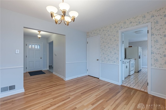 entrance foyer with light hardwood / wood-style floors and a notable chandelier