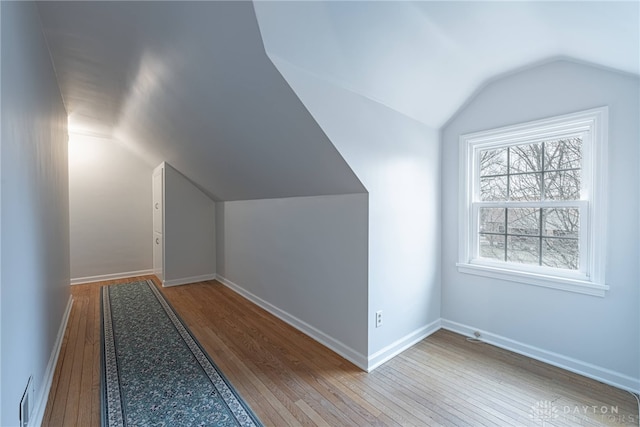 additional living space featuring vaulted ceiling and hardwood / wood-style floors