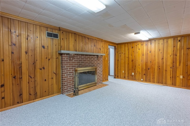 unfurnished living room with a fireplace, wooden walls, and carpet