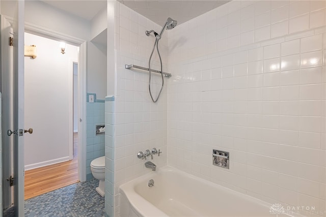 bathroom with tiled shower / bath, tile walls, and toilet