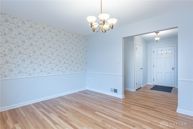 empty room featuring light hardwood / wood-style floors and a chandelier