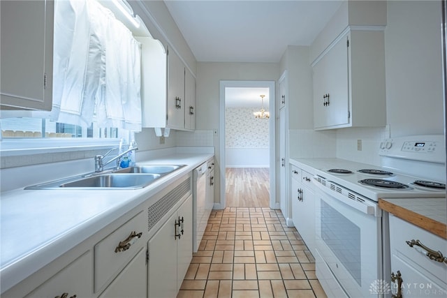 kitchen with sink, white appliances, a chandelier, and white cabinets