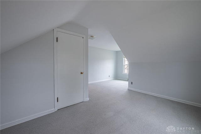 additional living space with light colored carpet and lofted ceiling