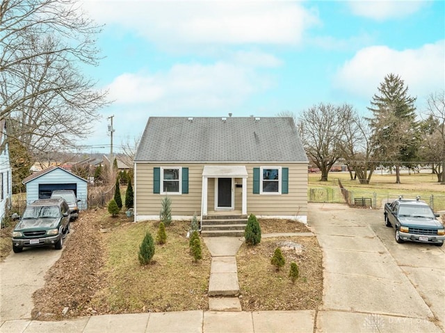 bungalow-style home featuring a garage, an outdoor structure, and a front lawn