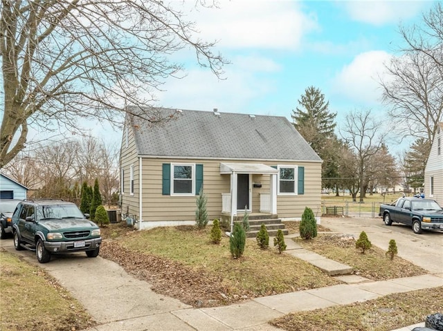 view of front of property featuring driveway, roof with shingles, and fence