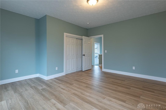 unfurnished bedroom featuring a closet, light hardwood / wood-style flooring, and a textured ceiling