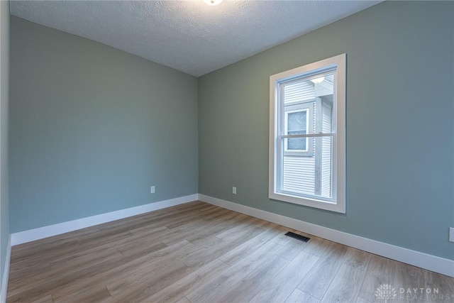 spare room featuring a textured ceiling and light wood-type flooring