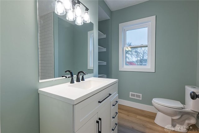 bathroom with hardwood / wood-style flooring, vanity, toilet, and a notable chandelier