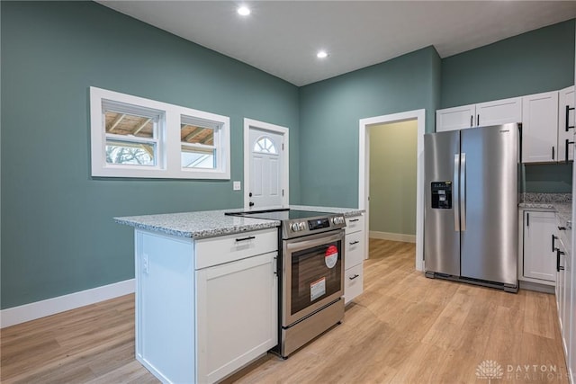 kitchen featuring white cabinetry, appliances with stainless steel finishes, light stone countertops, and a kitchen island