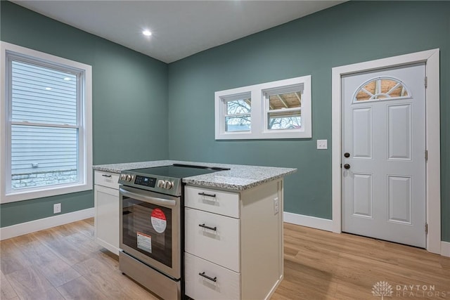 kitchen with white cabinetry, a healthy amount of sunlight, and stainless steel range with electric stovetop