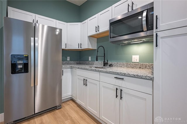 kitchen featuring light stone counters, sink, stainless steel appliances, and white cabinets