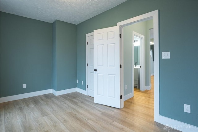 unfurnished bedroom featuring a closet, a textured ceiling, and light wood-type flooring