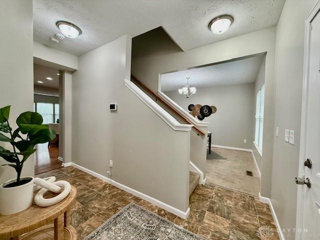 entryway featuring a wealth of natural light, a chandelier, and a textured ceiling