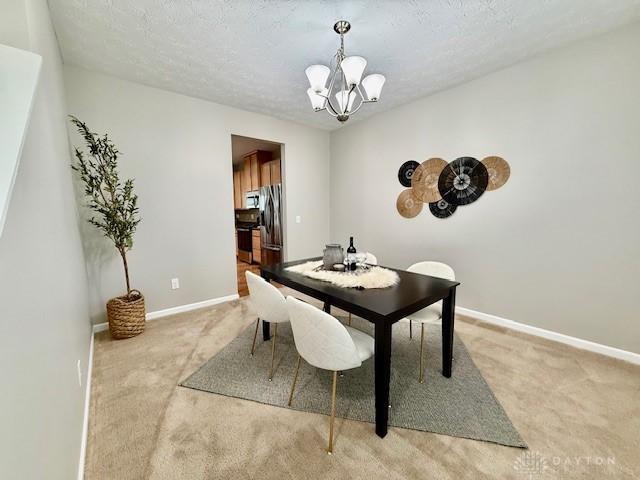 dining space with an inviting chandelier, carpet floors, and a textured ceiling