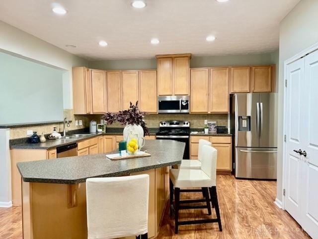 kitchen with stainless steel appliances, a center island, sink, and a breakfast bar area