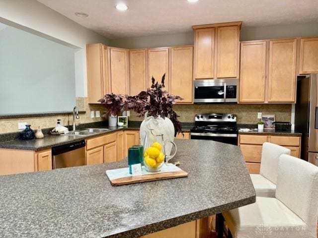 kitchen with tasteful backsplash, appliances with stainless steel finishes, sink, and light brown cabinetry