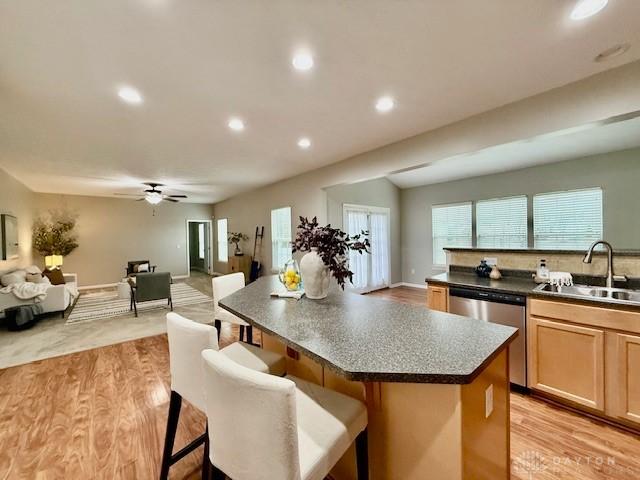 kitchen with a breakfast bar area, a kitchen island, sink, and stainless steel dishwasher