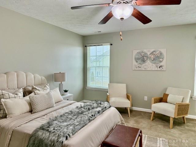 carpeted bedroom with ceiling fan and a textured ceiling