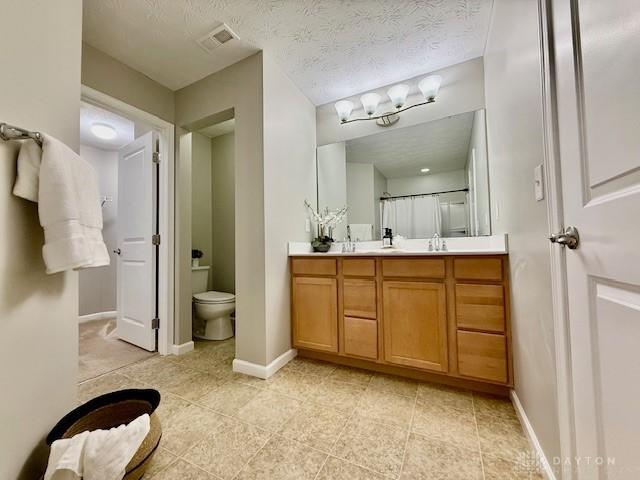 bathroom with vanity, a textured ceiling, and toilet