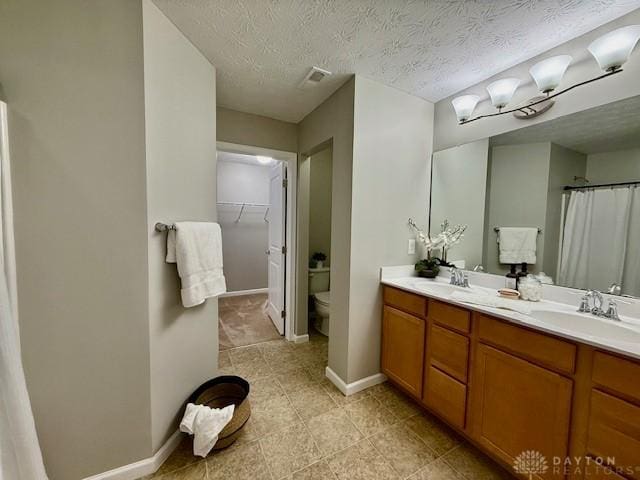 bathroom featuring vanity, a textured ceiling, and toilet