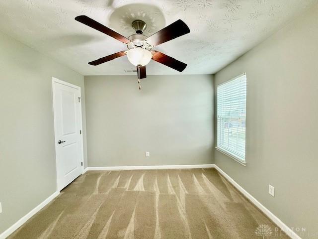 spare room featuring ceiling fan, a textured ceiling, and carpet flooring