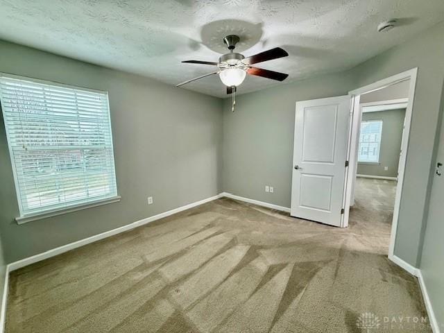 unfurnished bedroom with ceiling fan, light colored carpet, and a textured ceiling