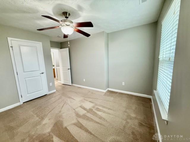 unfurnished bedroom with light colored carpet and ceiling fan