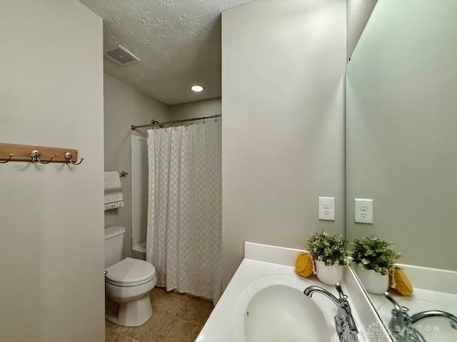 full bathroom featuring toilet, a textured ceiling, vanity, shower / bath combination with curtain, and tile patterned flooring