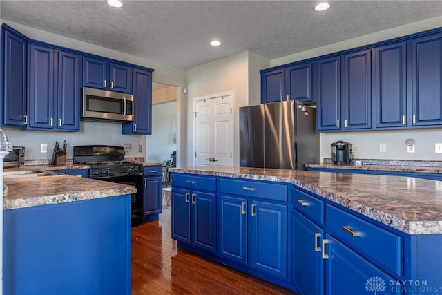 kitchen featuring blue cabinetry, appliances with stainless steel finishes, dark wood-style flooring, and recessed lighting