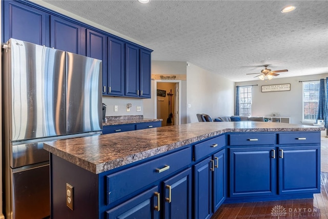 kitchen with freestanding refrigerator, open floor plan, dark countertops, and blue cabinetry