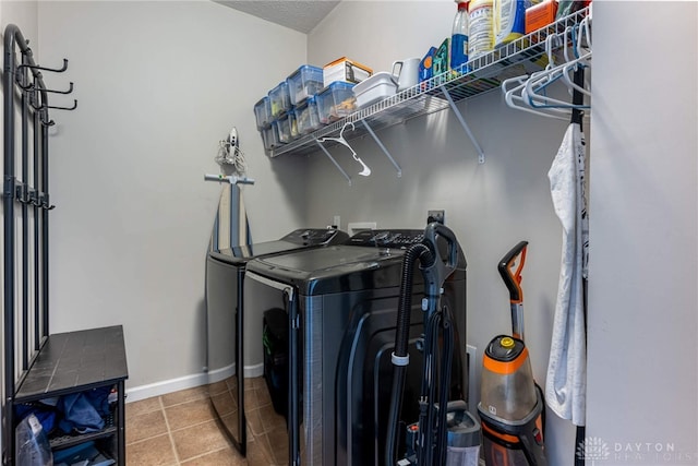 clothes washing area featuring laundry area, tile patterned flooring, baseboards, and washer and clothes dryer