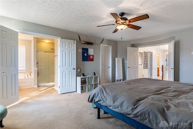 bedroom featuring a ceiling fan, ensuite bathroom, a textured ceiling, and light colored carpet