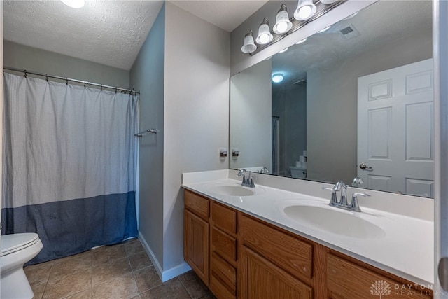 bathroom featuring a sink, a textured ceiling, toilet, and double vanity