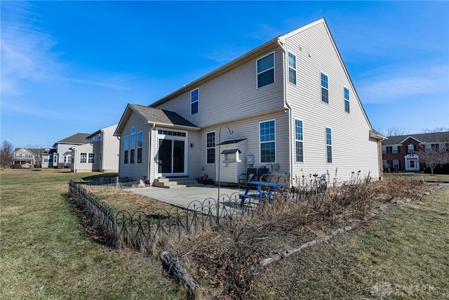 back of property with entry steps, a patio area, a yard, and a residential view