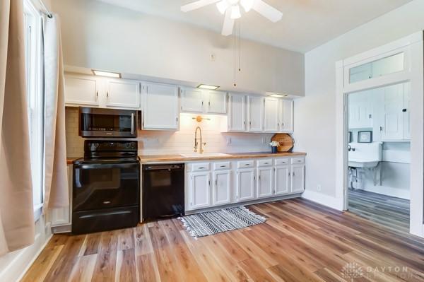 201 E Somers St, Eaton, OH 45320 - kitchen featuring black appliances, a sink, white cabinetry, light wood-type flooring, and light countertops