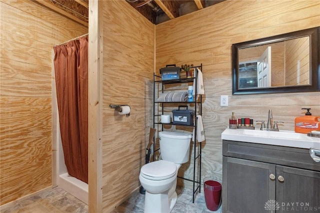 bathroom with vanity, wood walls, toilet, and a shower with shower curtain