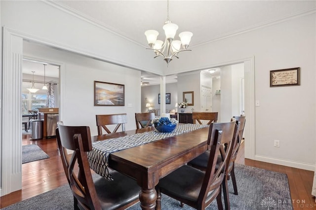 dining area with crown molding, dark hardwood / wood-style flooring, and an inviting chandelier