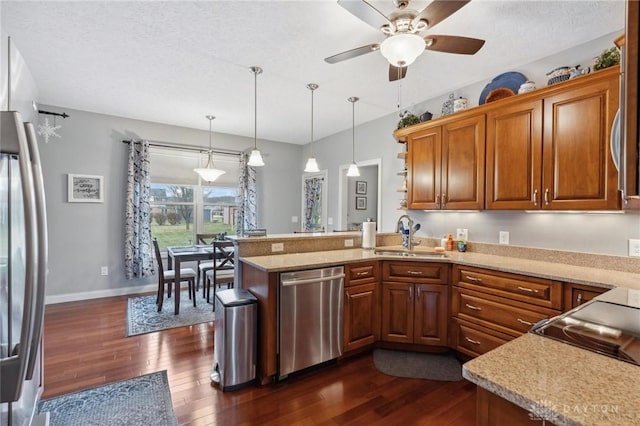 kitchen featuring appliances with stainless steel finishes, pendant lighting, sink, dark hardwood / wood-style flooring, and kitchen peninsula