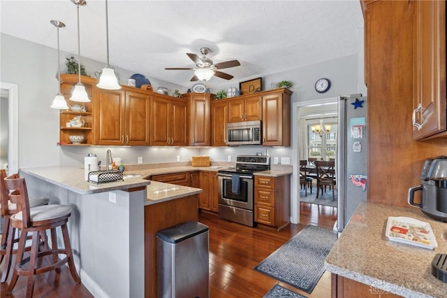 kitchen featuring a breakfast bar area, light stone counters, decorative light fixtures, kitchen peninsula, and stainless steel appliances