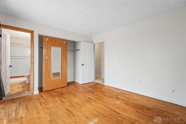 unfurnished bedroom with a closet, ensuite bathroom, and light hardwood / wood-style flooring