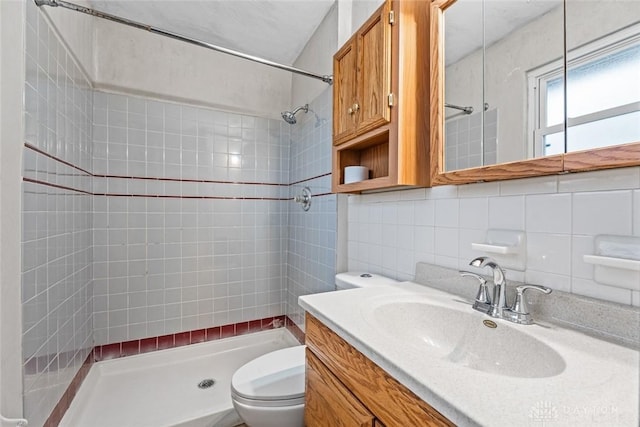 bathroom with tiled shower, toilet, tile walls, vanity, and decorative backsplash