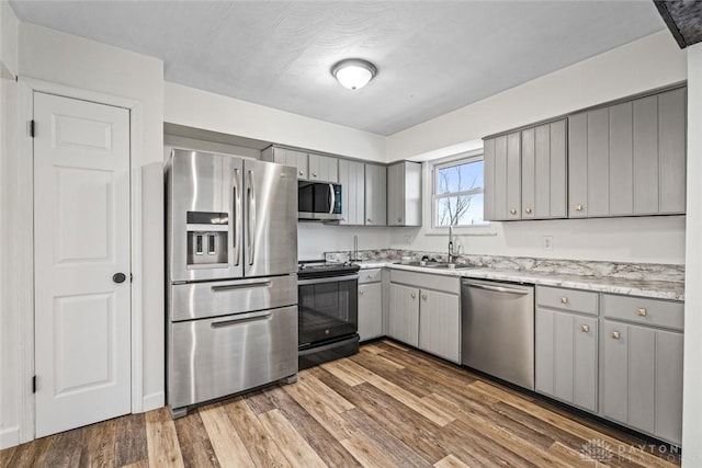 kitchen featuring hardwood / wood-style flooring, stainless steel appliances, gray cabinets, and sink