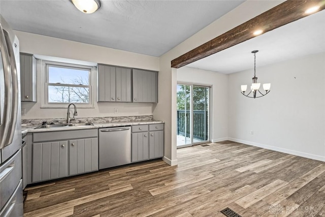 kitchen with gray cabinets, appliances with stainless steel finishes, dark hardwood / wood-style floors, sink, and hanging light fixtures